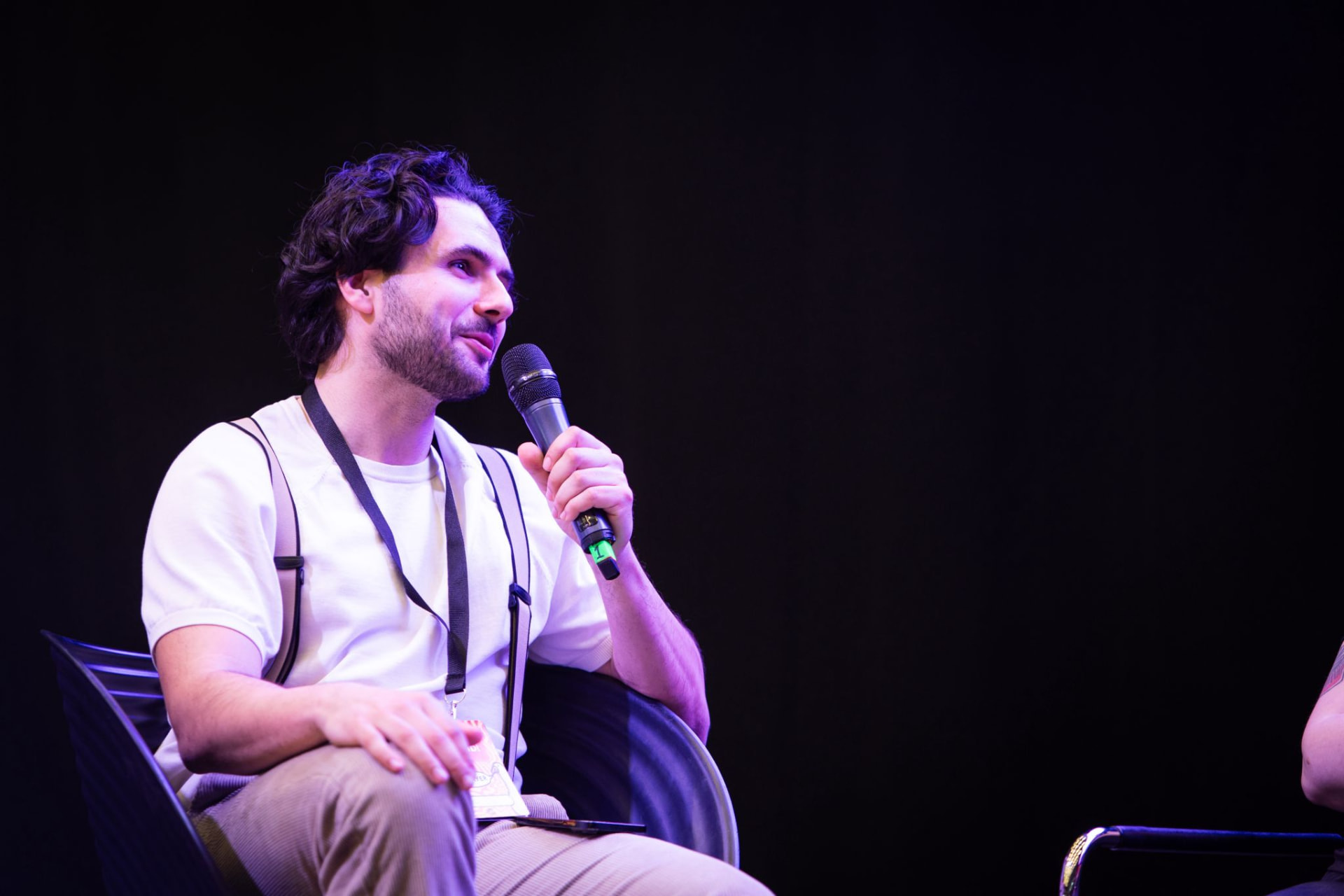 Trim Biba speaking on stage with a microphone under purple light