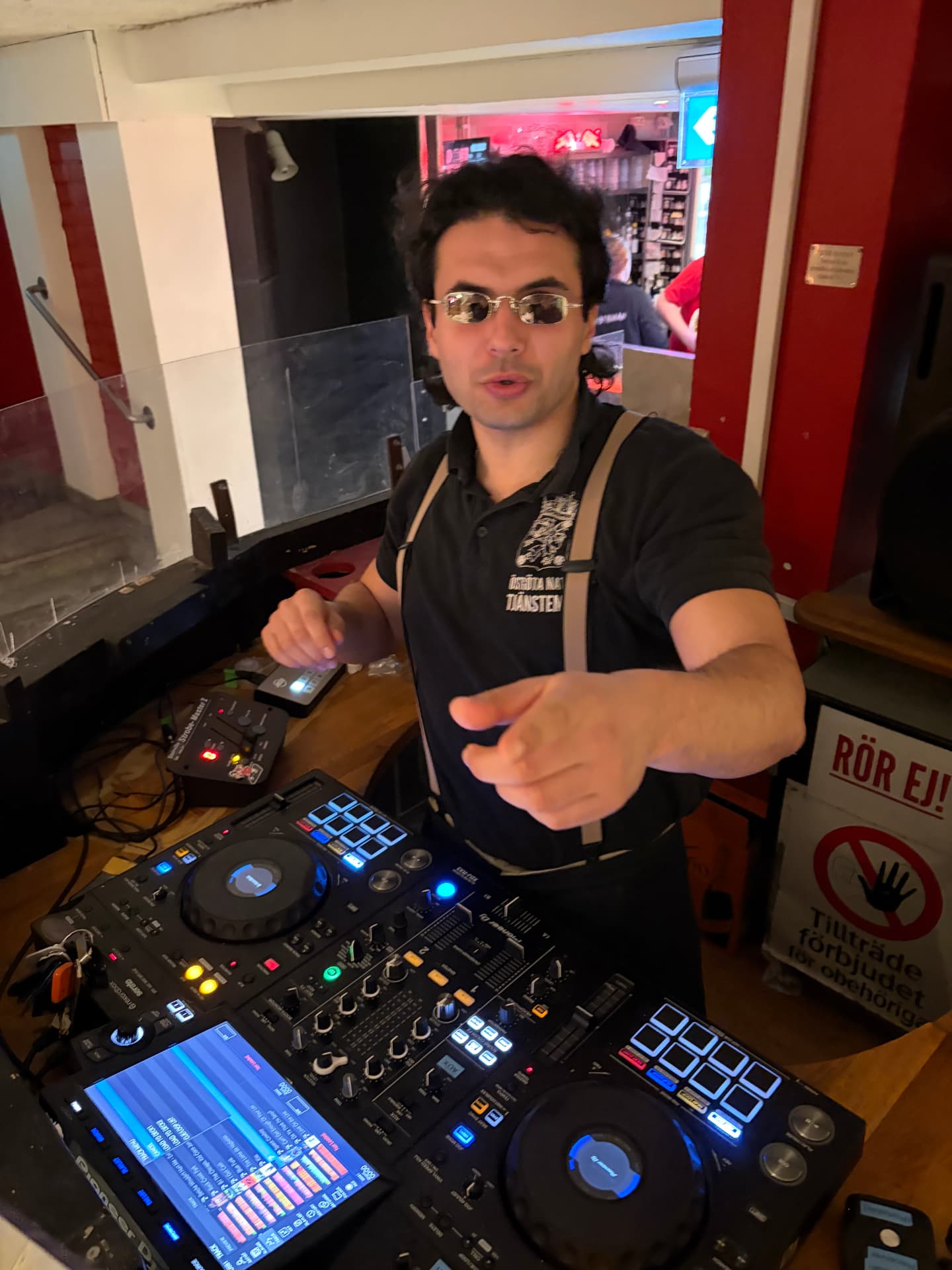 Trim Biba pointing at the camera from the DJ booth in a bar