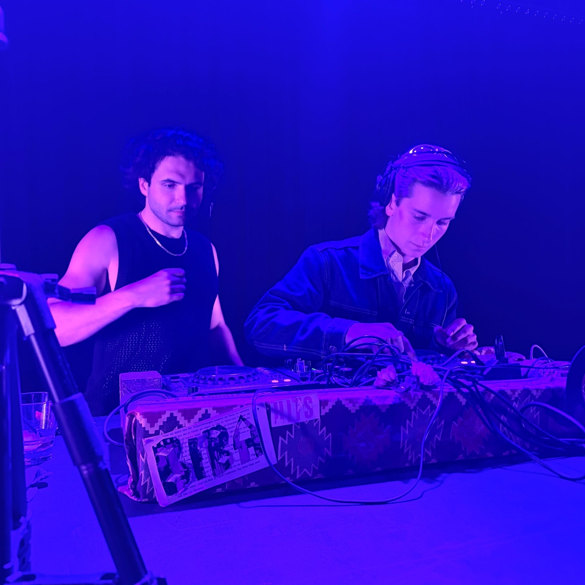 Trim Biba playing back-to-back behind a BIBA banner in blue light
